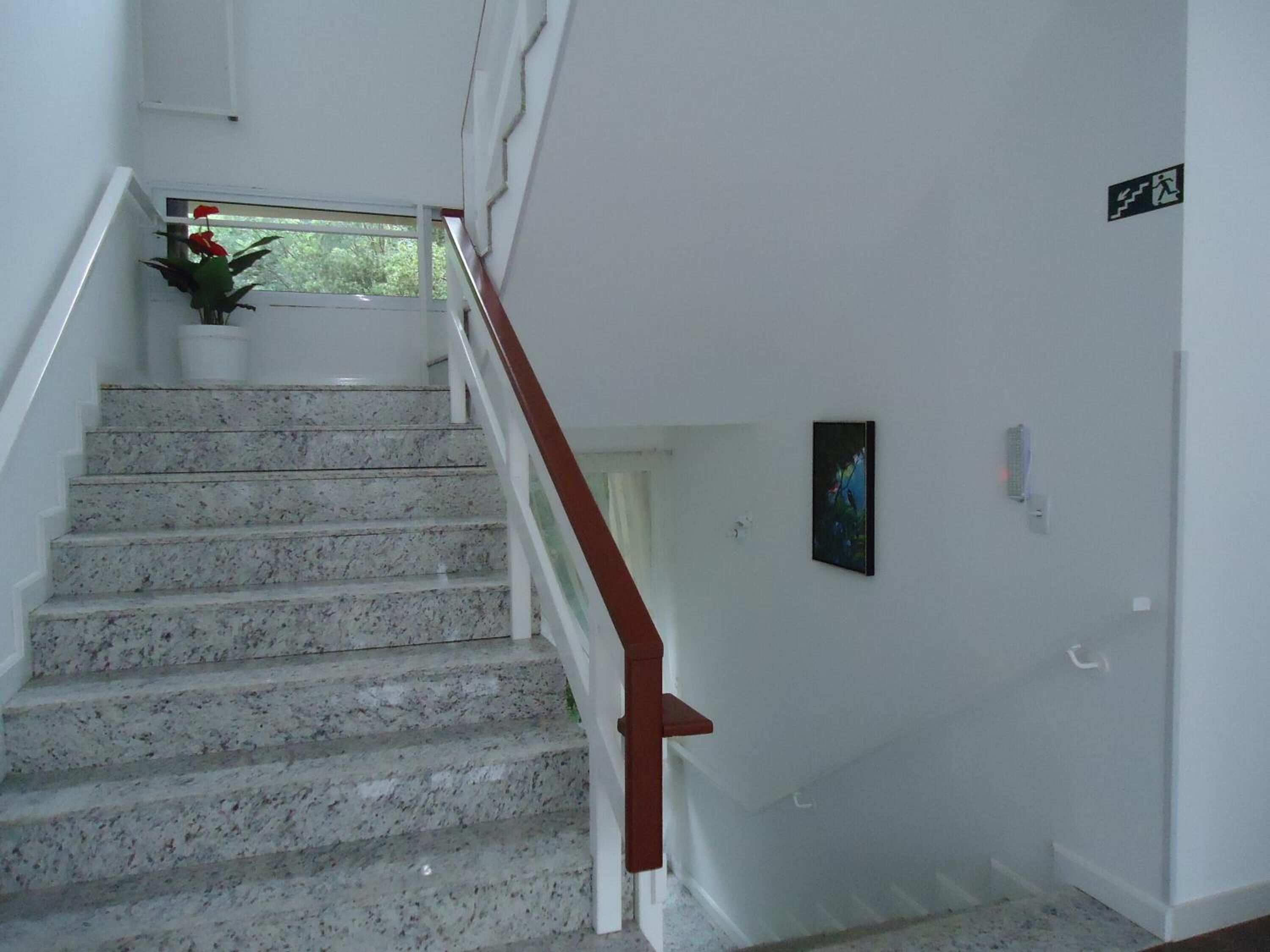 A staircase with white walls and a red handrail leading to a landing.