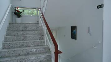 A staircase with white walls and a red handrail leading to a landing.