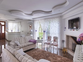 A living room with a sofa, armchairs, a fireplace, and a view of greenery outside.