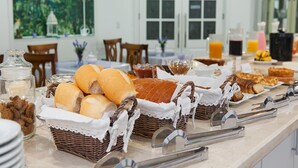 A breakfast buffet with various breads and pastries, a coffee station, and a juice bar. - Pousada Perfume de Canela (Canela)