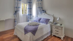 A bedroom with a bed, nightstands, and a window with curtains. - Pousada Perfume de Canela (Canela)