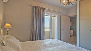 A bedroom with a bed, a lamp, a chandelier, and a sliding door leading to a balcony.