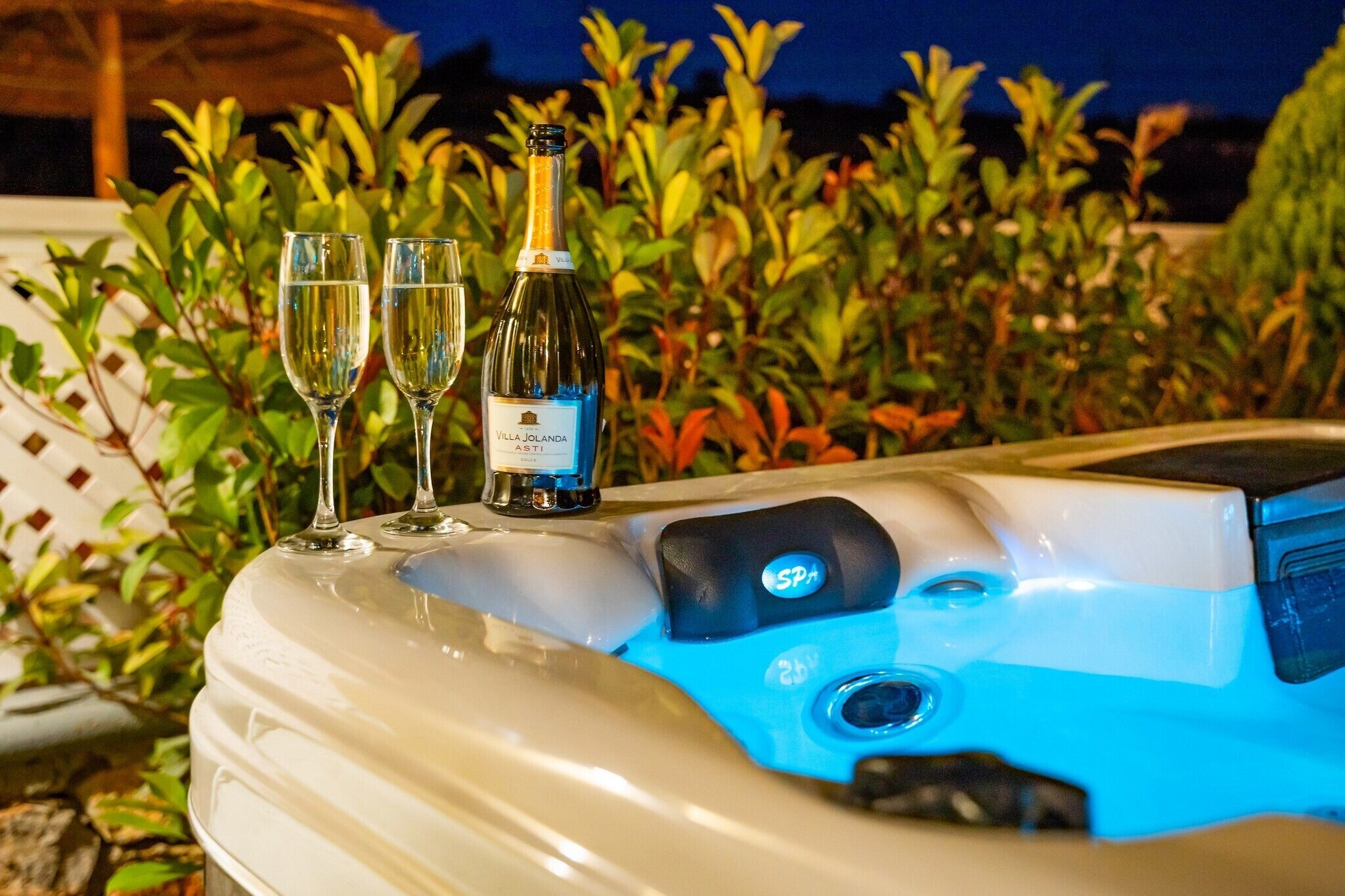 Banyera d'hidromassatge d'un spa amb dues copes de vi i una ampolla de vi Villa Jolanda.