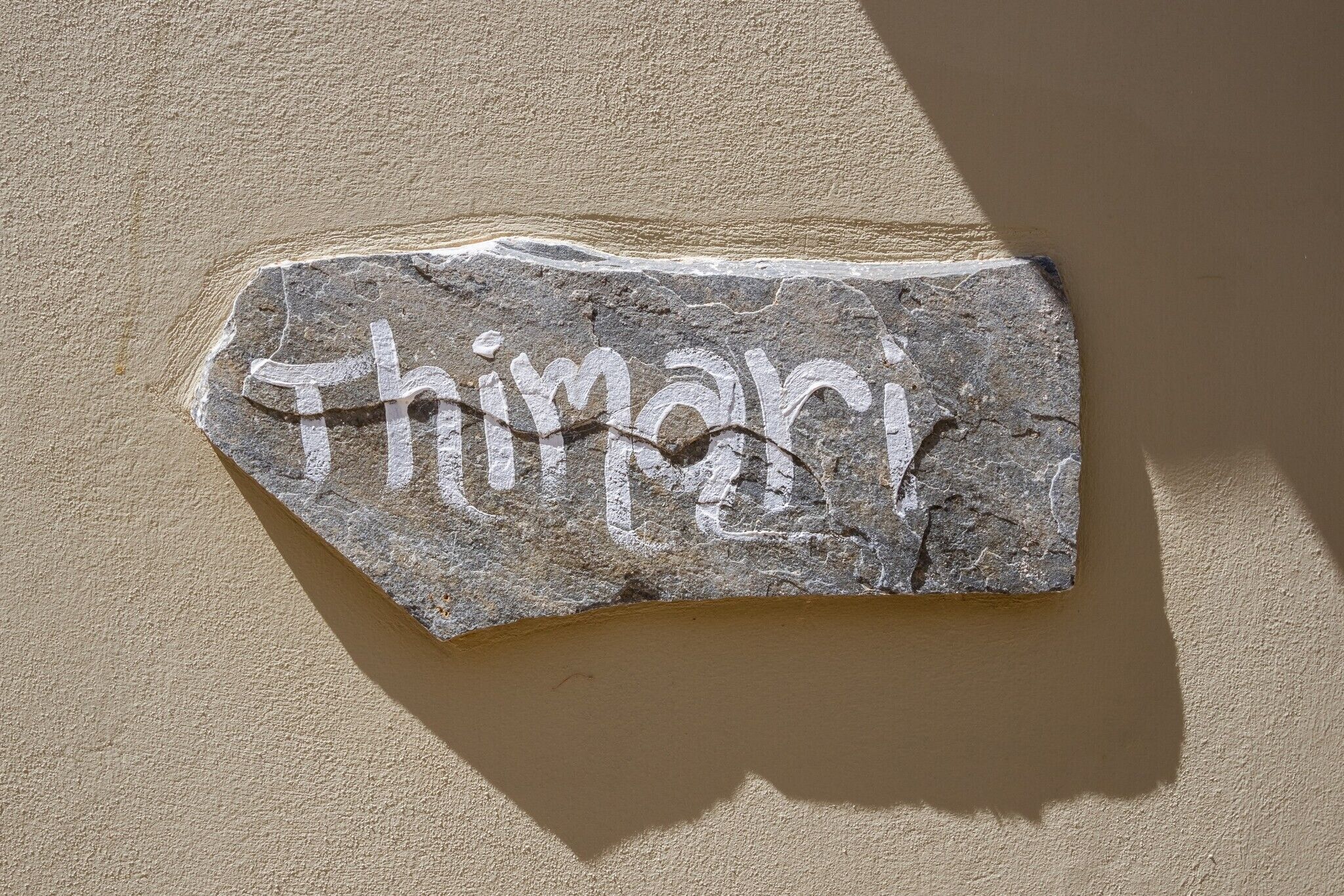 Un letrero de piedra con el nombre "Thimari" grabado, sujeto a una pared.