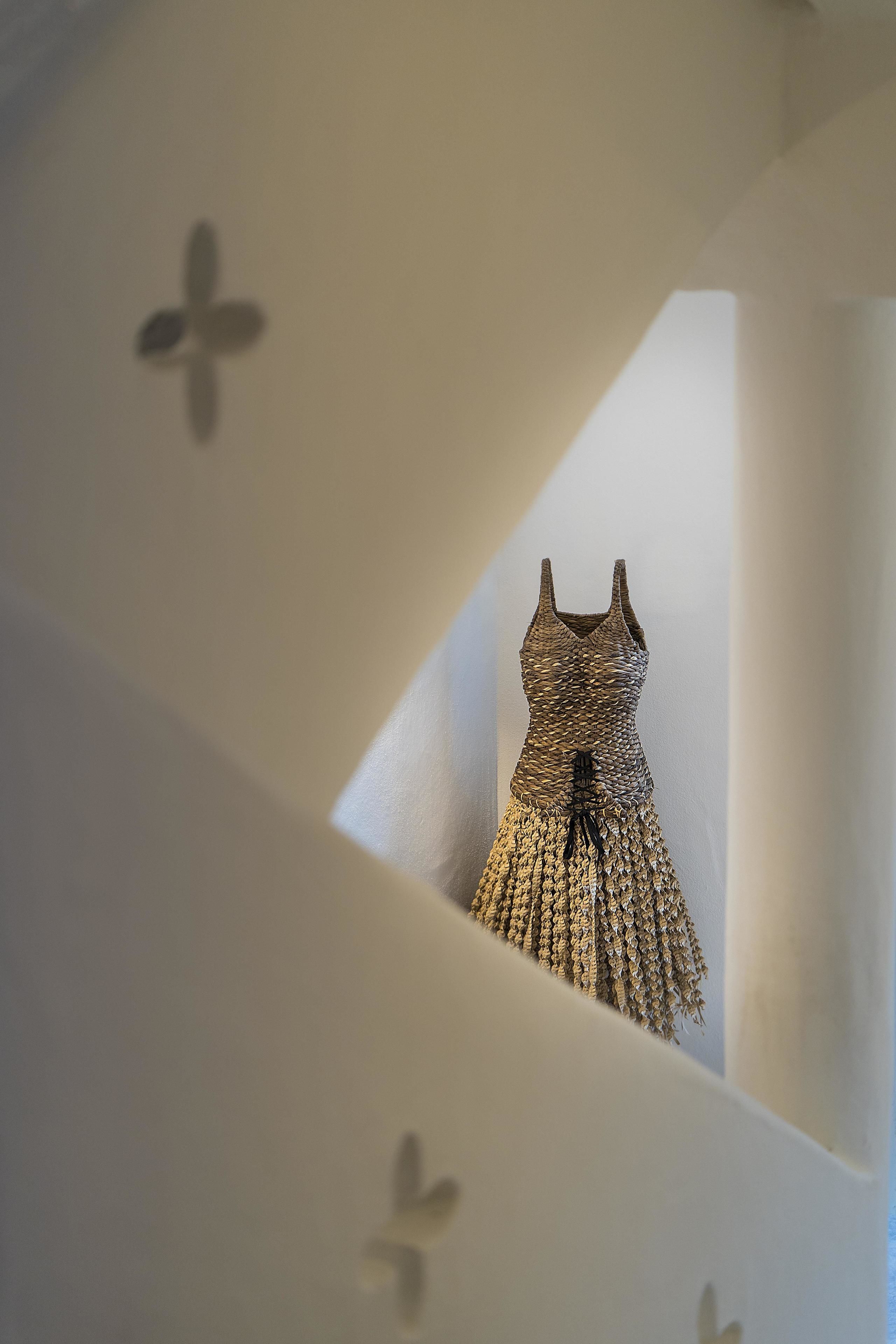 A room with a unique architectural design featuring a wall with a cut-out section revealing a textured wall hanging.