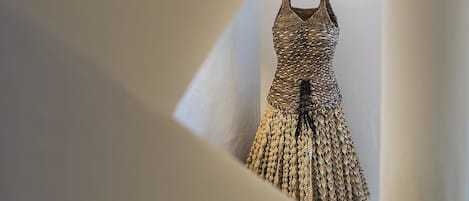 A room with a unique architectural design featuring a wall with a cut-out section revealing a textured wall hanging.