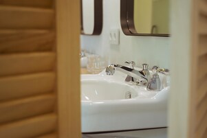 A bathroom with a white sink, two faucets, and a mirror.