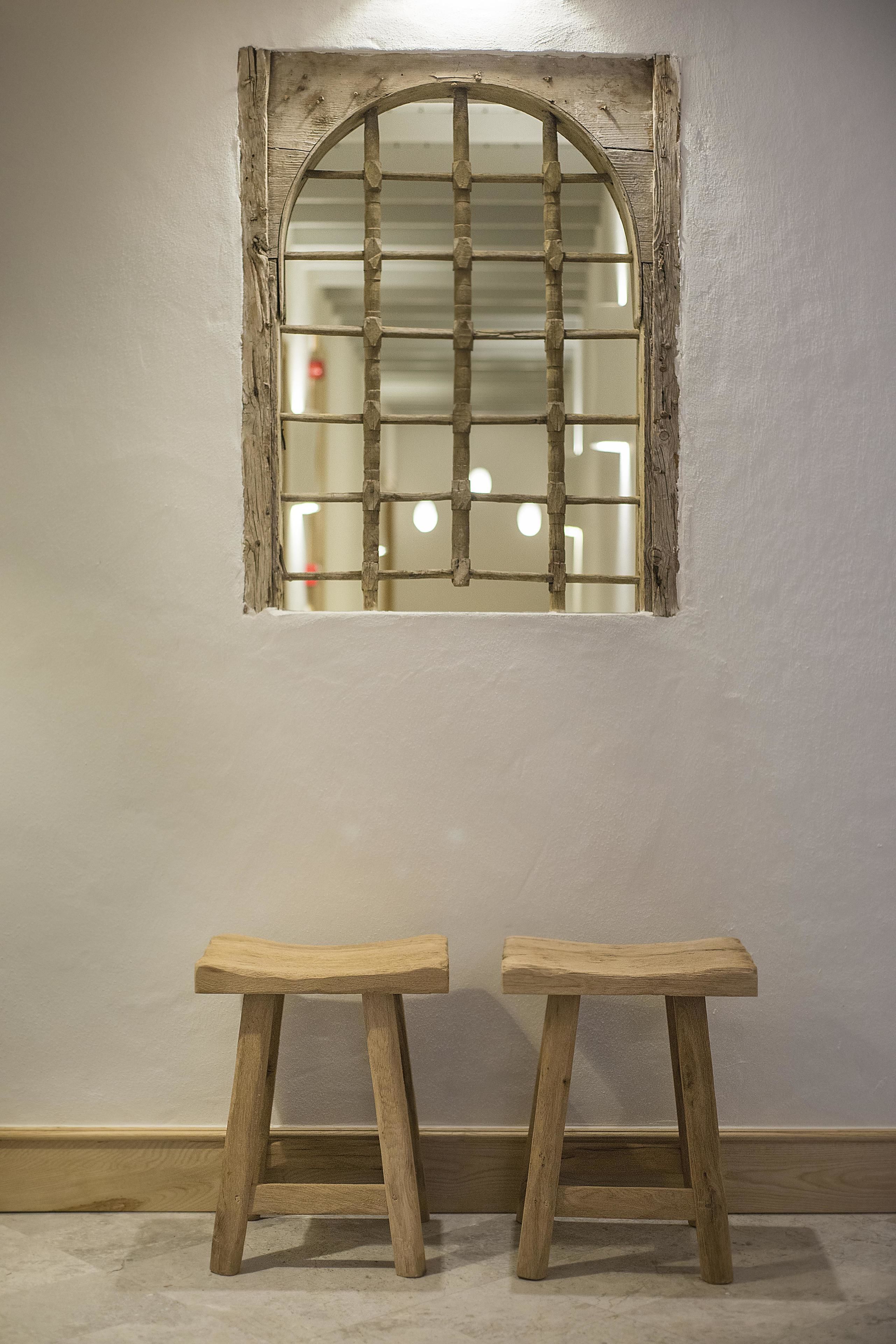 A room with a rustic wooden window and two wooden stools.