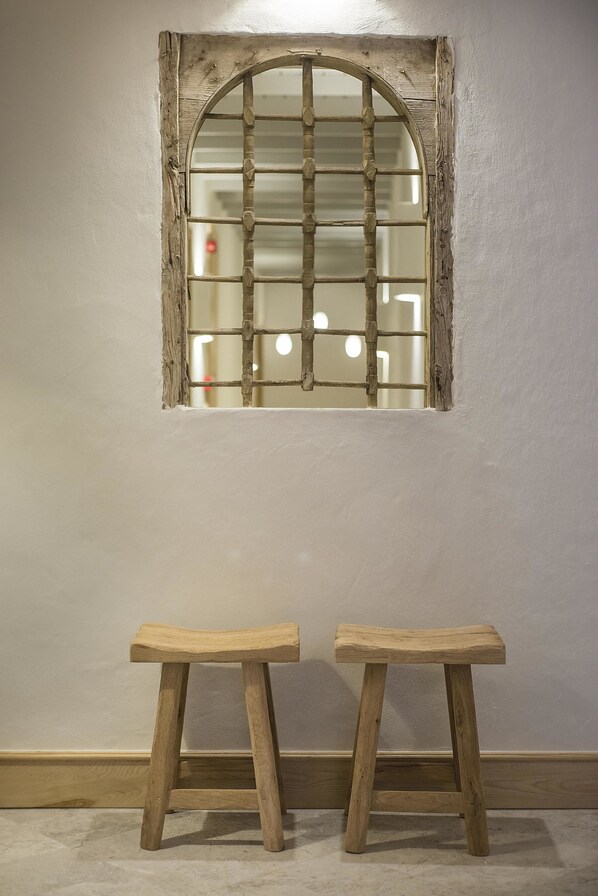 A room with a rustic wooden window and two wooden stools.