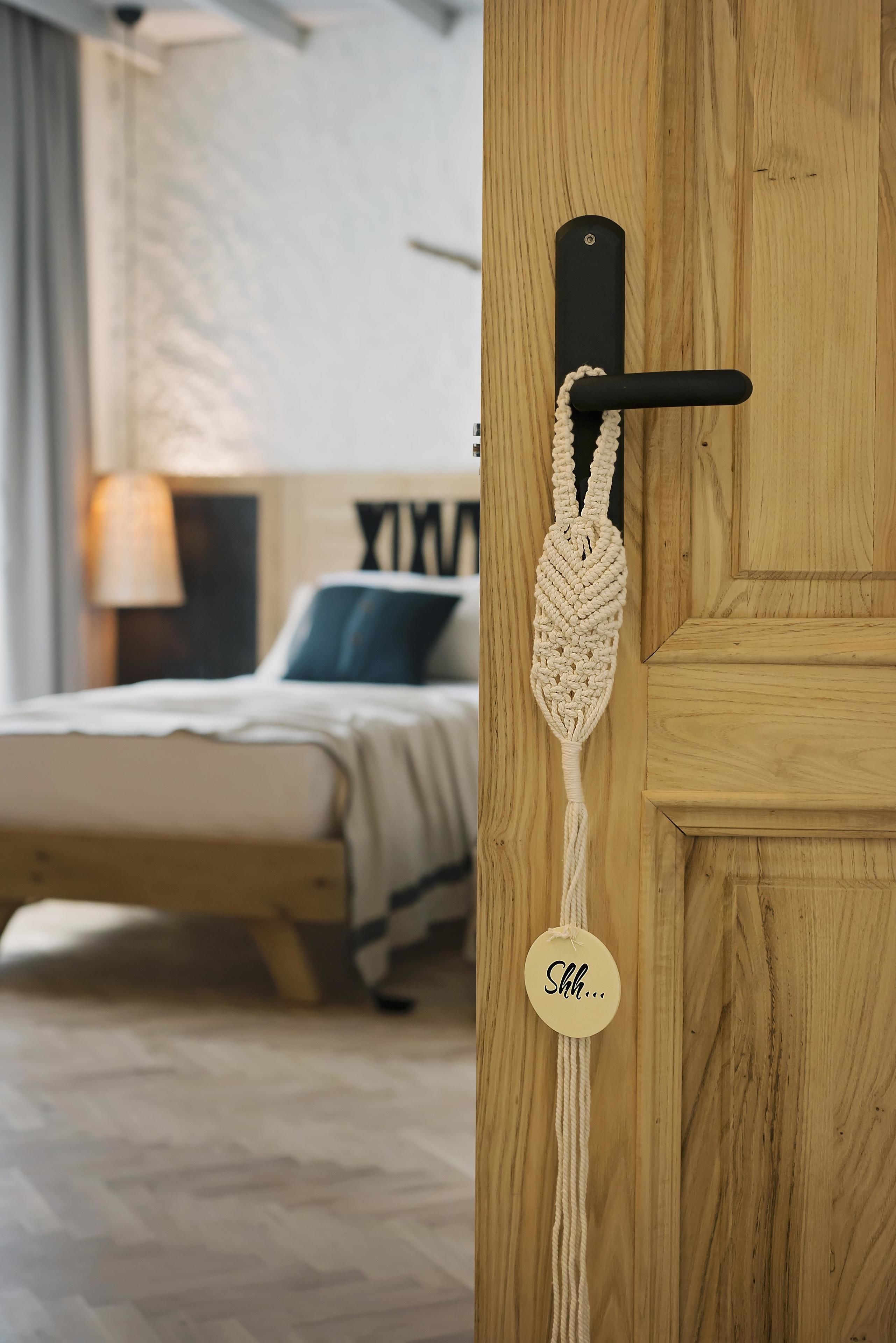 Une porte en bois ornée d’un porte-clés en macramé et d’une étiquette sur laquelle on peut lire : « Chut… ».