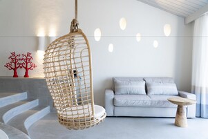 Uma sala de estar moderna com uma cadeira suspensa, um sofá cinza e uma pequena mesa de madeira.