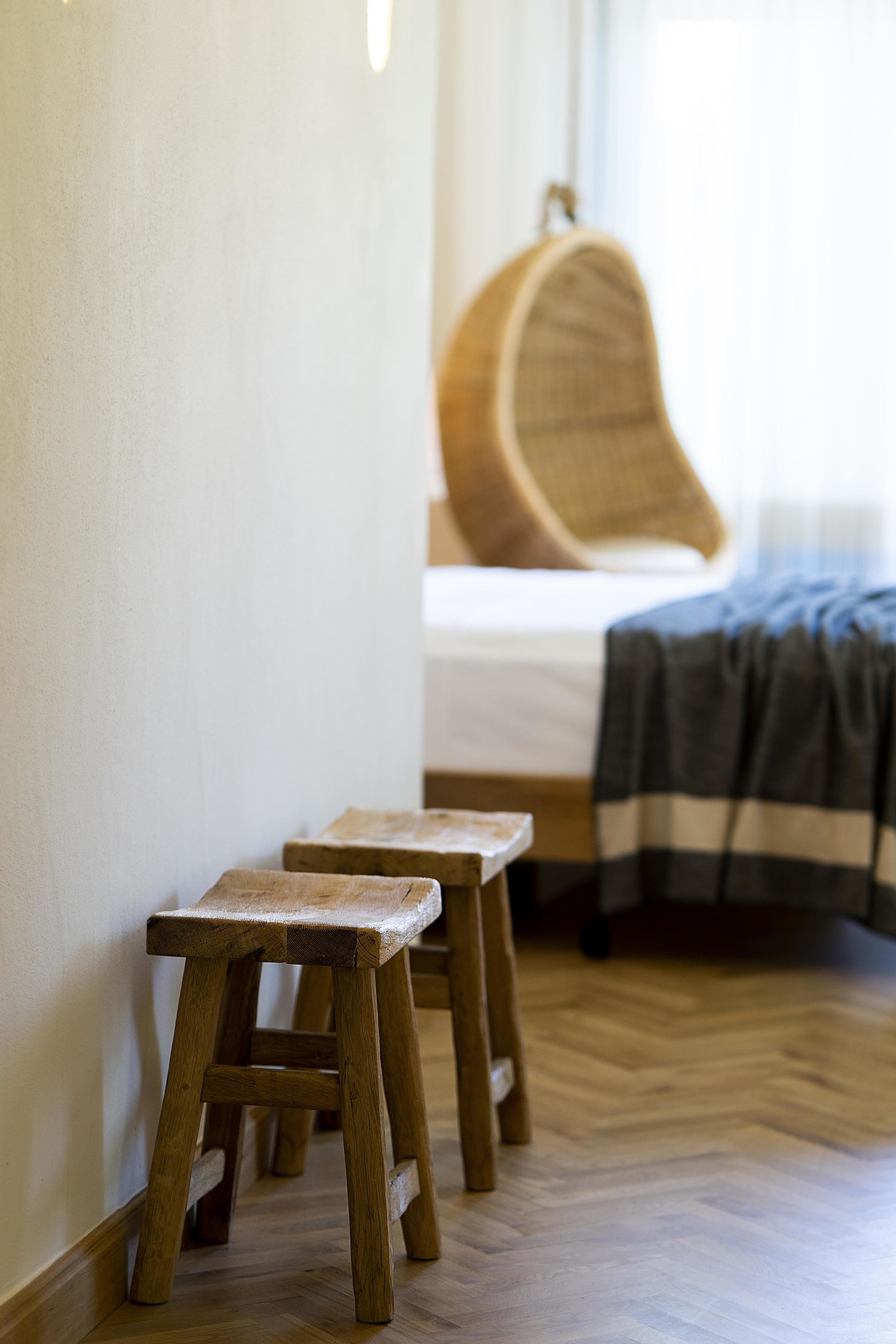 A wooden stool in a room with a herringbone floor pattern.