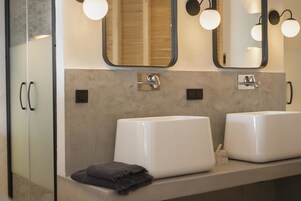 Un baño con dos lavamanos, un espejo e iluminación en la pared.