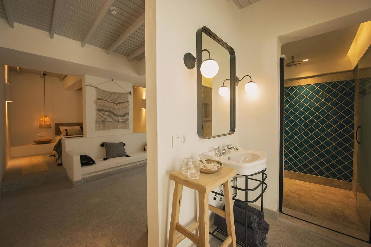 A modern bathroom with a white sink, a large mirror, and a shower with a green tiled wall.