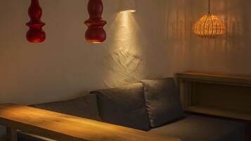 A cozy seating area with a wooden bench and a cushioned bench, illuminated by three pendant lights.