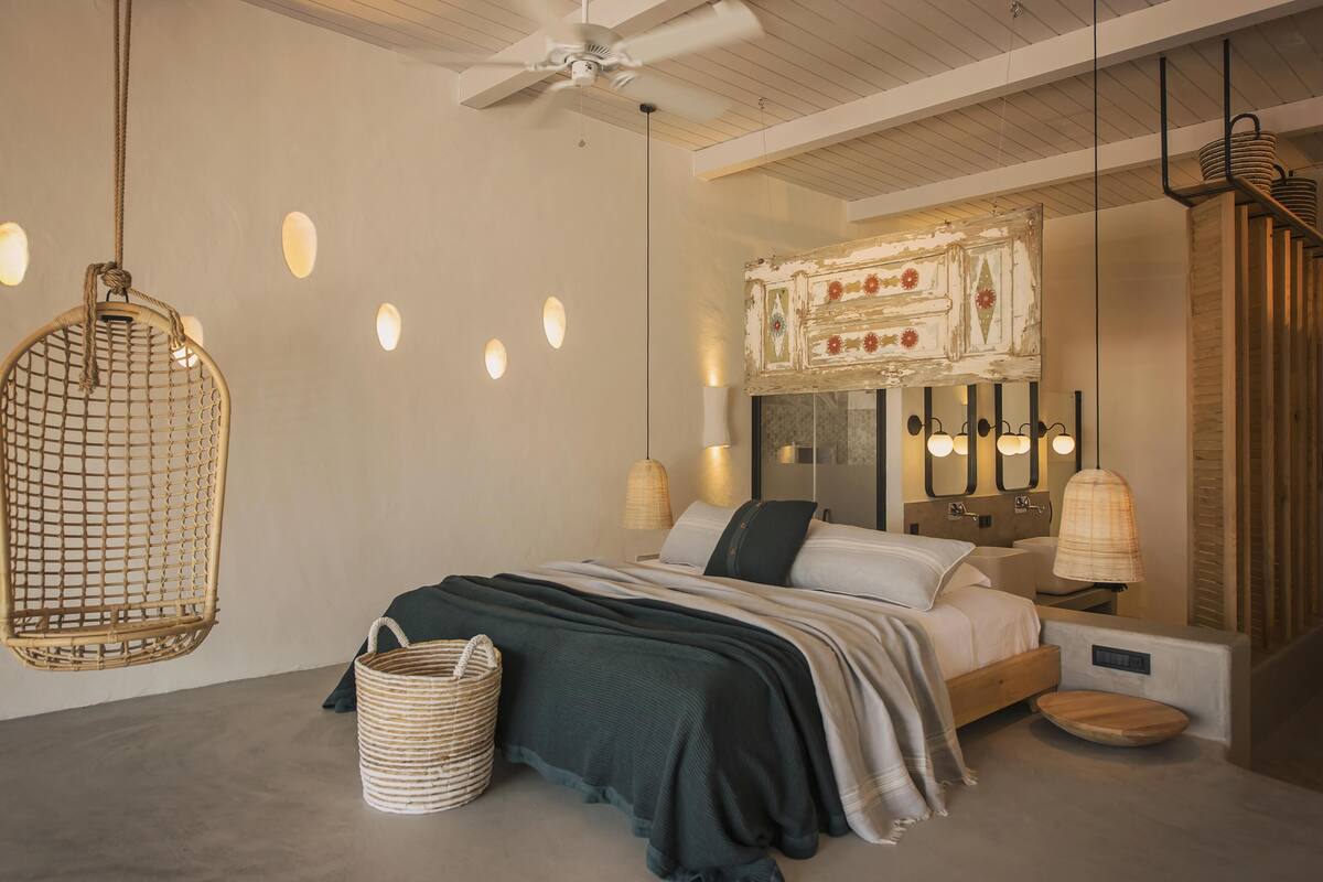 A modern bedroom with a bed, hanging chair, and bedside lamps.