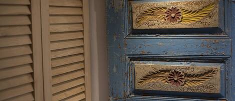 A blue door with decorative floral patterns and a window with horizontal blinds.