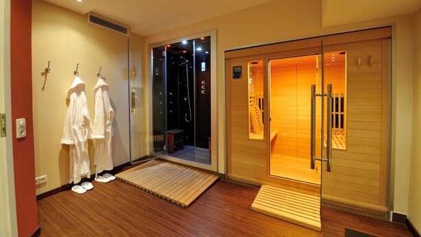 Ein Hotelzimmer mit Holzboden, einer Glastür zum Duschbereich und einer Holzbank davor.