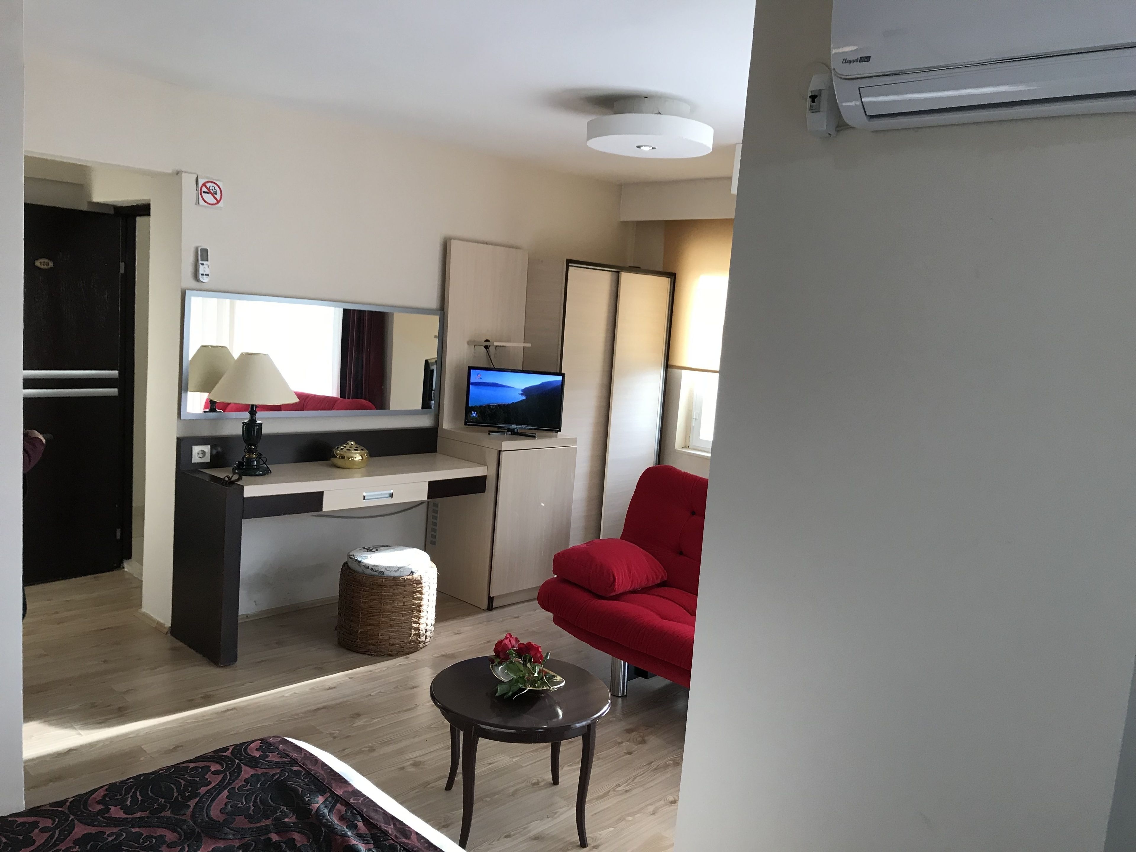 Un espacio habitable compacto con kitchenette, comedor y zona de estar con una silla roja.