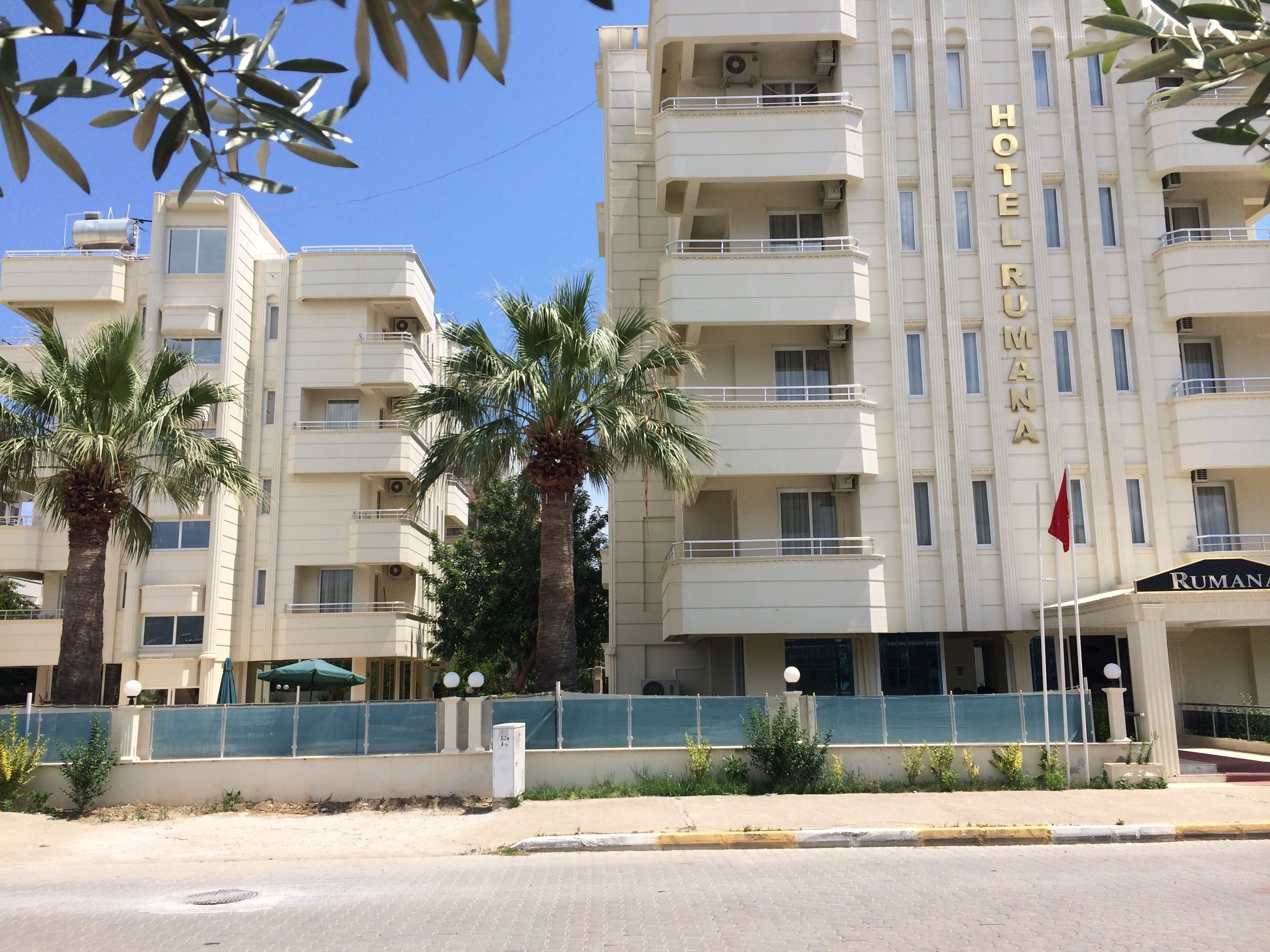 Un hotel de varios pisos, con balcones y palmeras frente a él.