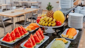 Een buffet tafel met diverse soorten fruit en groenten, waaronder watermeloen, bananen, ananas en meloen.