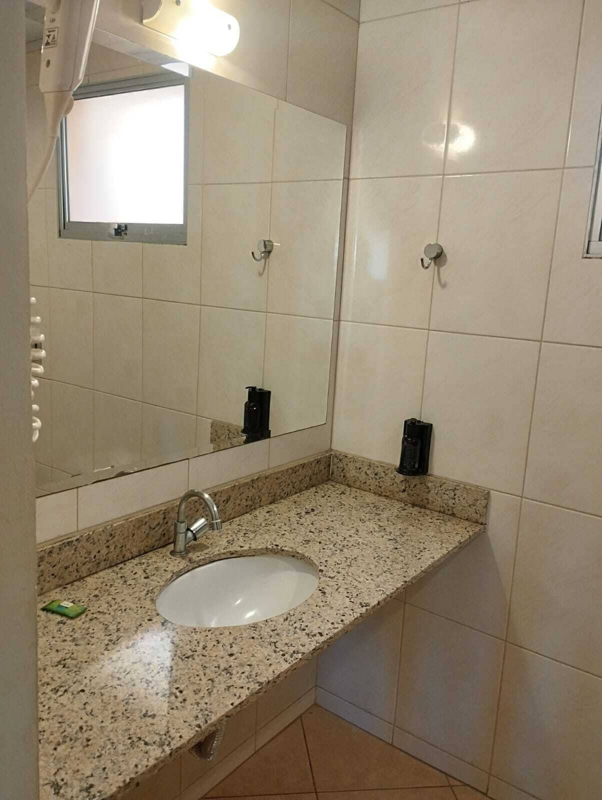 A bathroom with a sink, mirror, and tiled walls.
