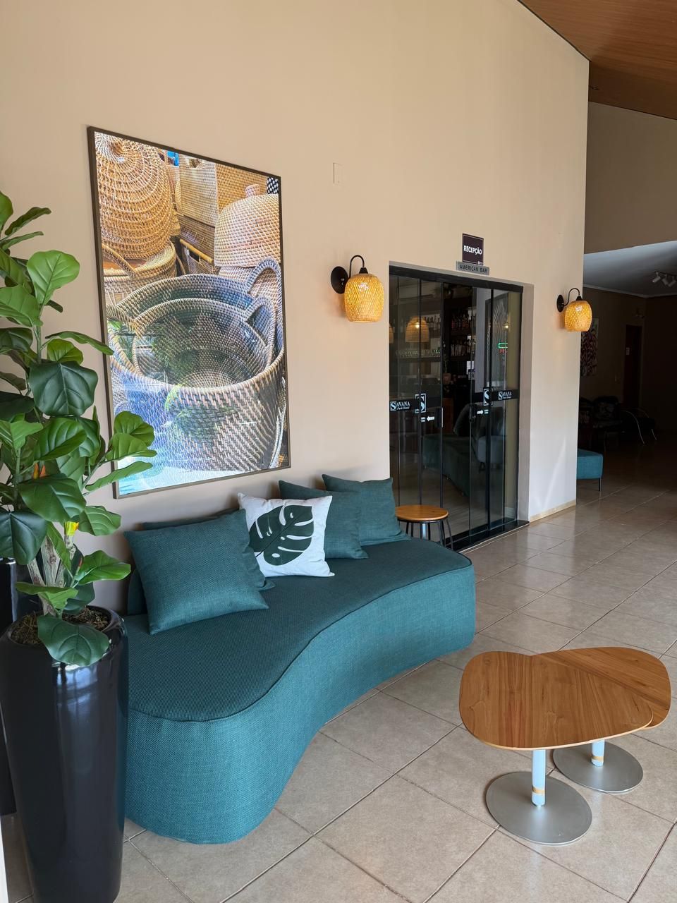Uma área de estar moderna com um sofá curvo verde-água, uma mesa redonda de madeira e um grande quadro abstrato na parede.