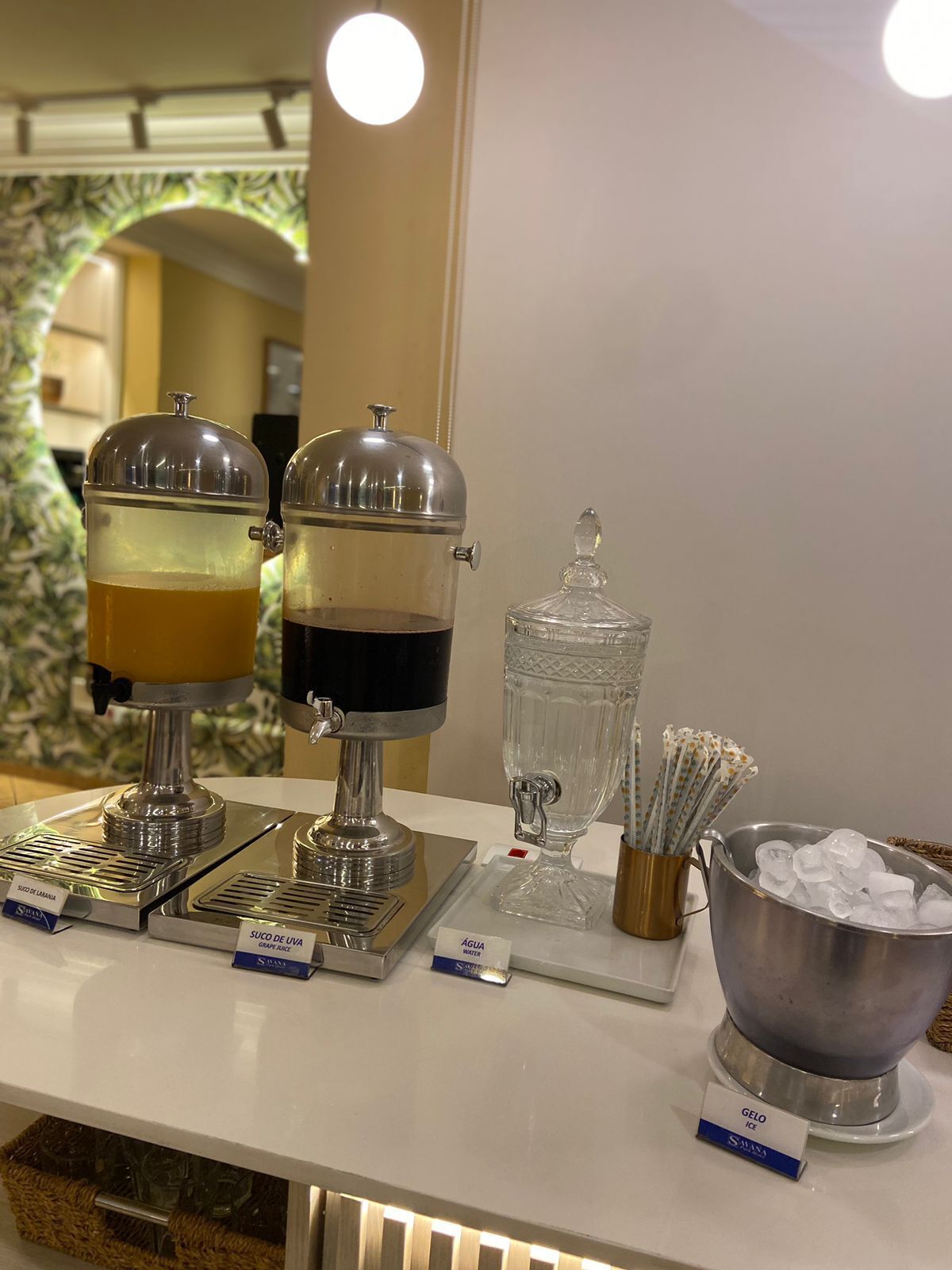 A beverage station with two dispensers, a water dispenser, and a bowl of ice.