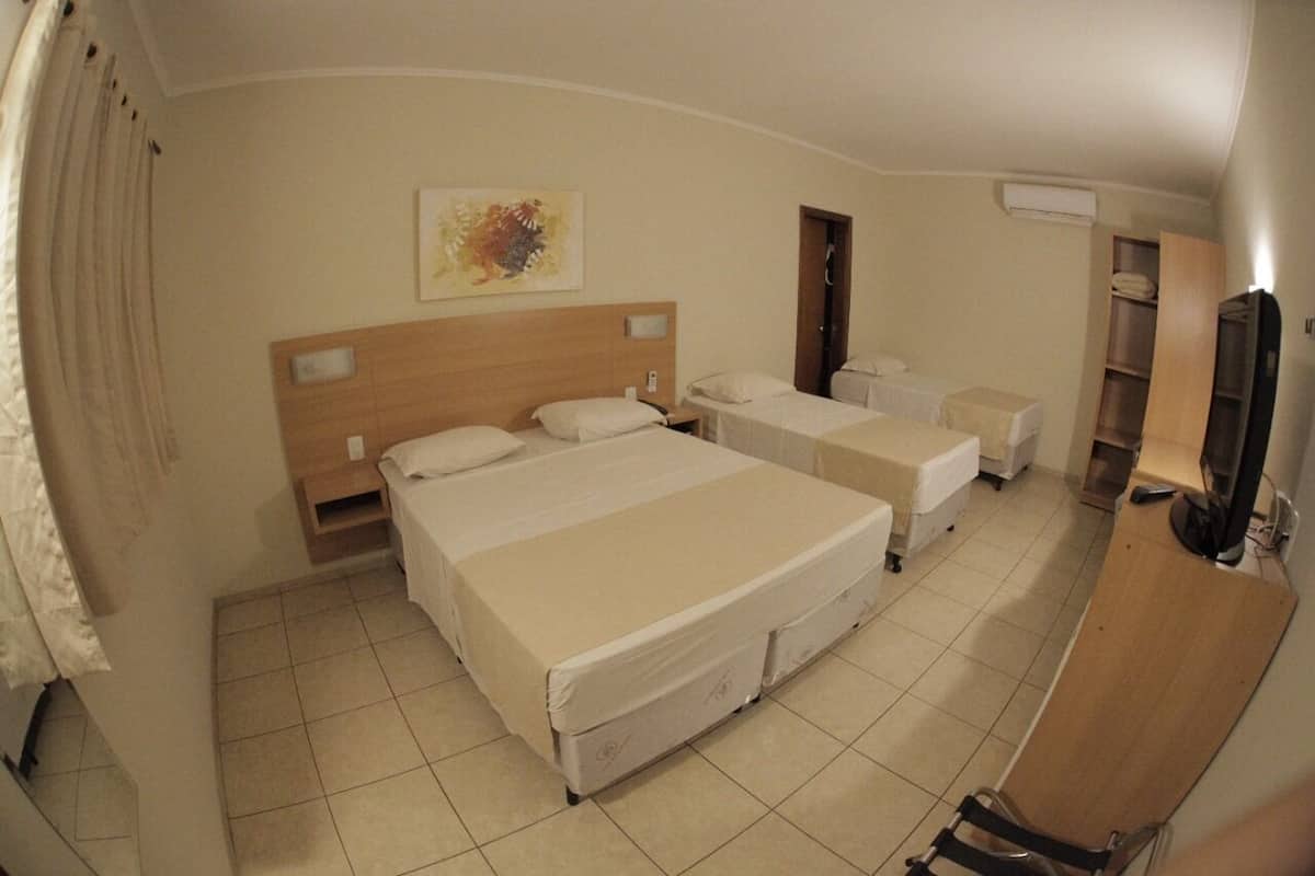 Une chambre d’hôtel avec deux lits, une tête de lit en bois, un téléviseur à écran plat et un tableau au mur.
