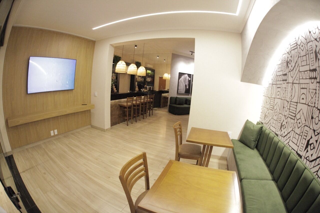 Un interior moderno con una pared de madera, un televisor de pantalla plana, una zona de bar con sillas y un sofá verde.