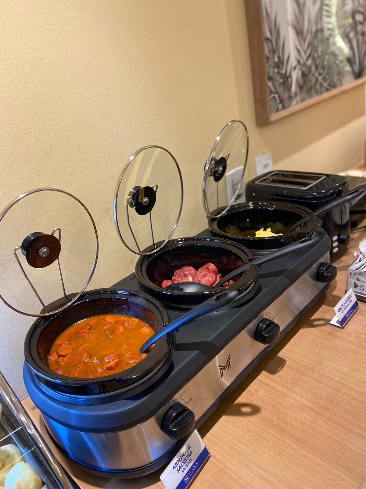 Ein Buffet mit verschiedenen Gerichten, darunter ein Eintopf und Würstchen, auf einem Edelstahlherd.