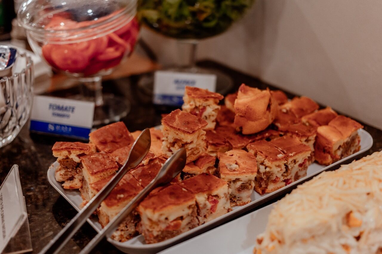 A buffet table with various dishes, including a tray of baked items and a bowl of salad.