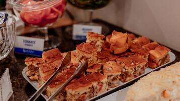 A buffet table with various dishes, including a tray of baked items and a bowl of salad.
