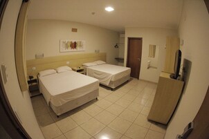 Habitación de hotel con dos camas, un armario de madera, un escritorio y un espejo.