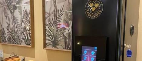 Una cafetera con pantalla digital, rodeada de alimentos y cestas de tazas.