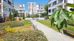 A residential building complex with multiple floors, balconies, and a central pathway. - 2-room WO07 - Platan (WO07) (Swinoujscie)