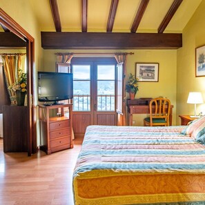 A bedroom with a bed, a desk, a television, and a window with a view. - Hotel Rey Don Jaime (Morella)