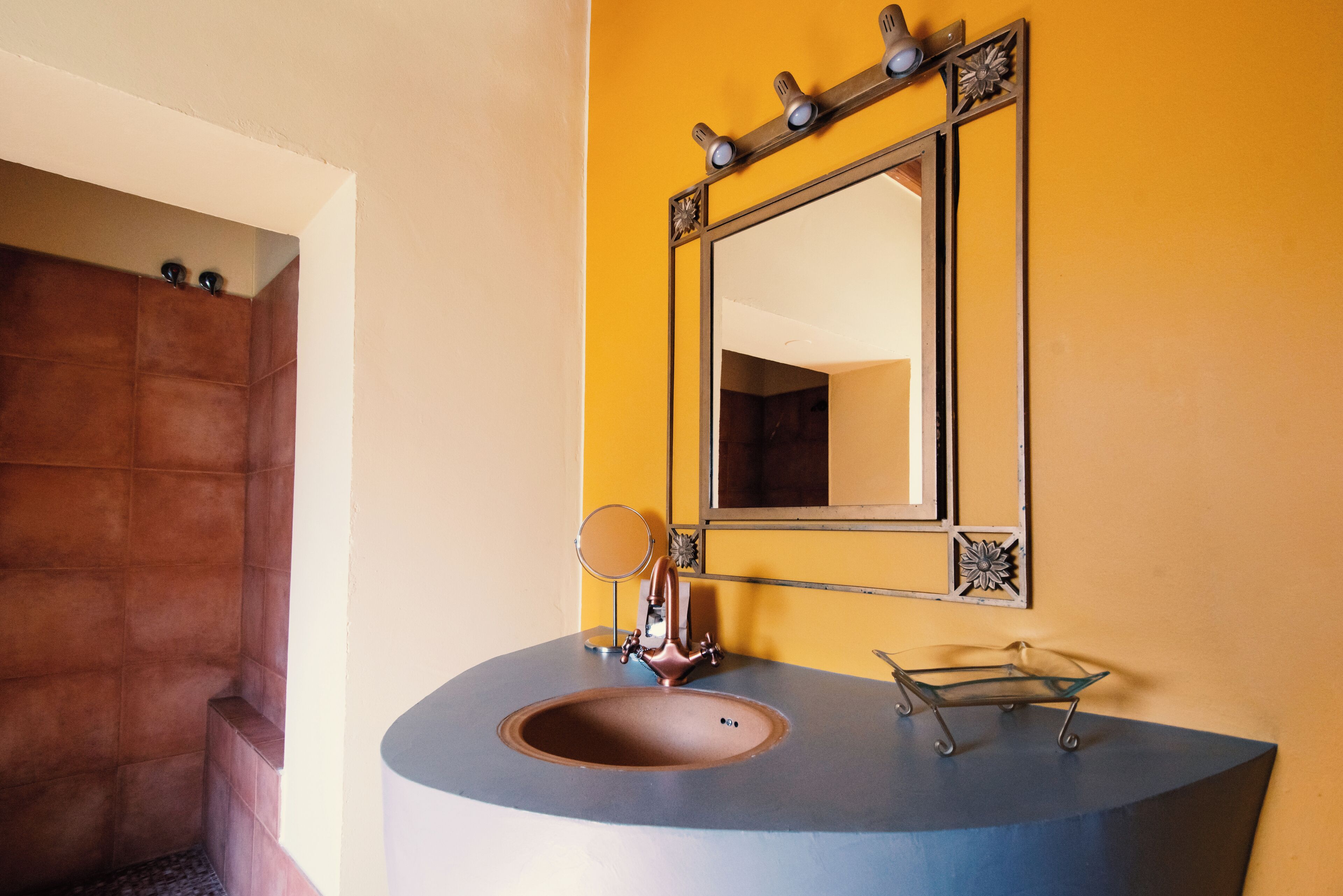 Un baño con lavamanos curvo, un espejo y zona de ducha.