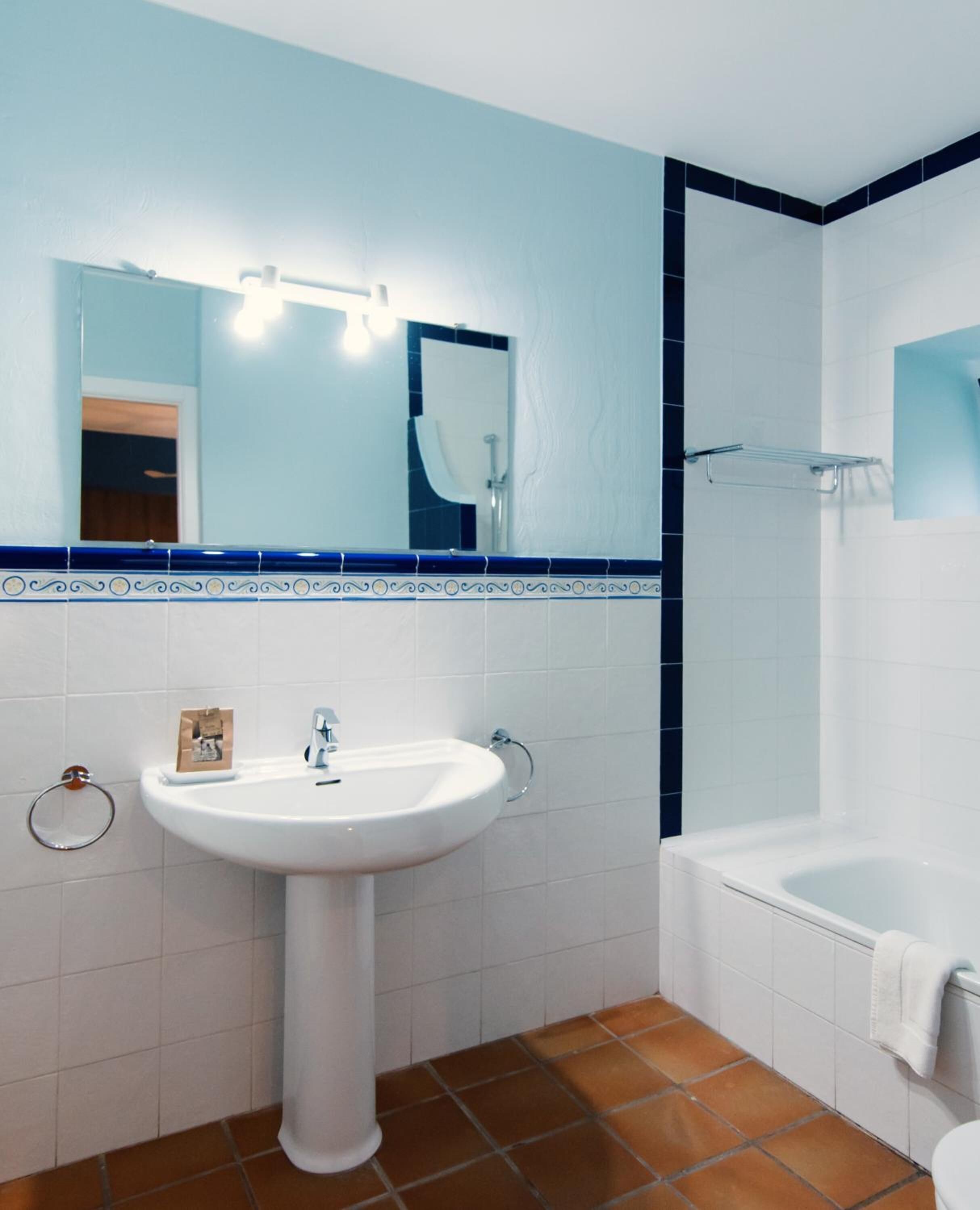 Un baño con lavamanos blanco, un espejo y una bañera.