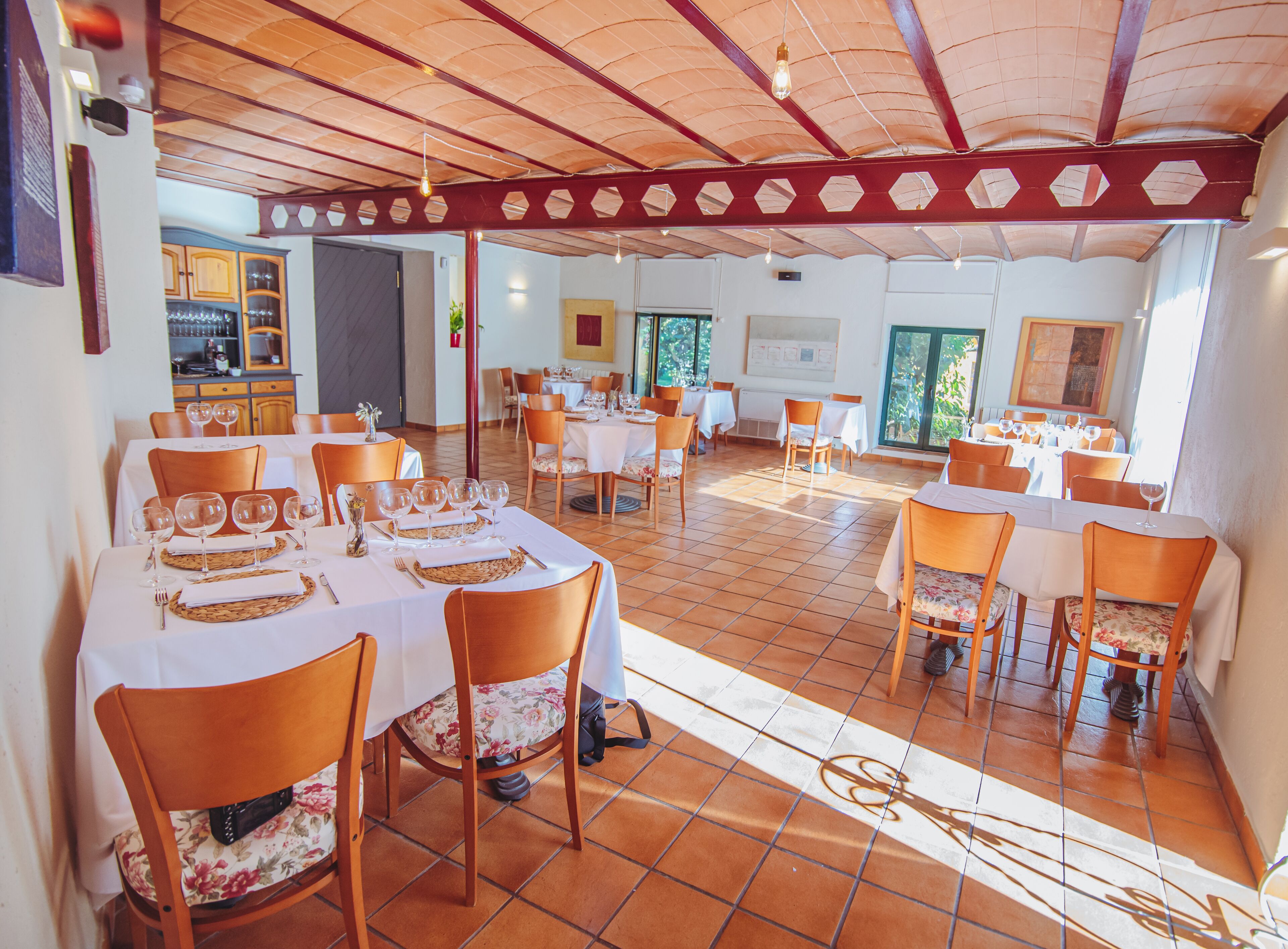 A spacious dining area with multiple tables set for dining, featuring chairs and wine glasses.