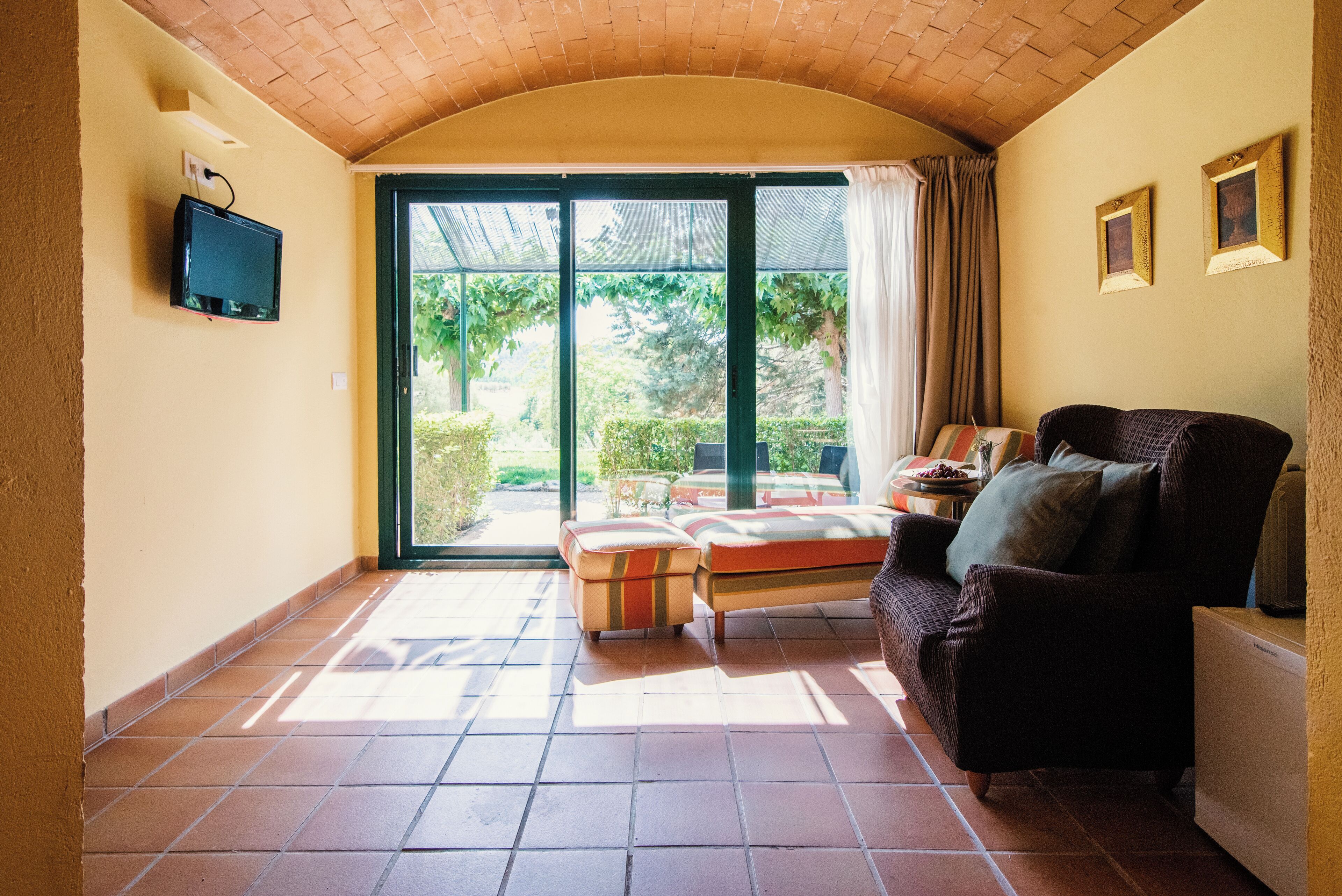 Una sala de estar con un sofá, un reposapiés y un televisor montado en la pared.