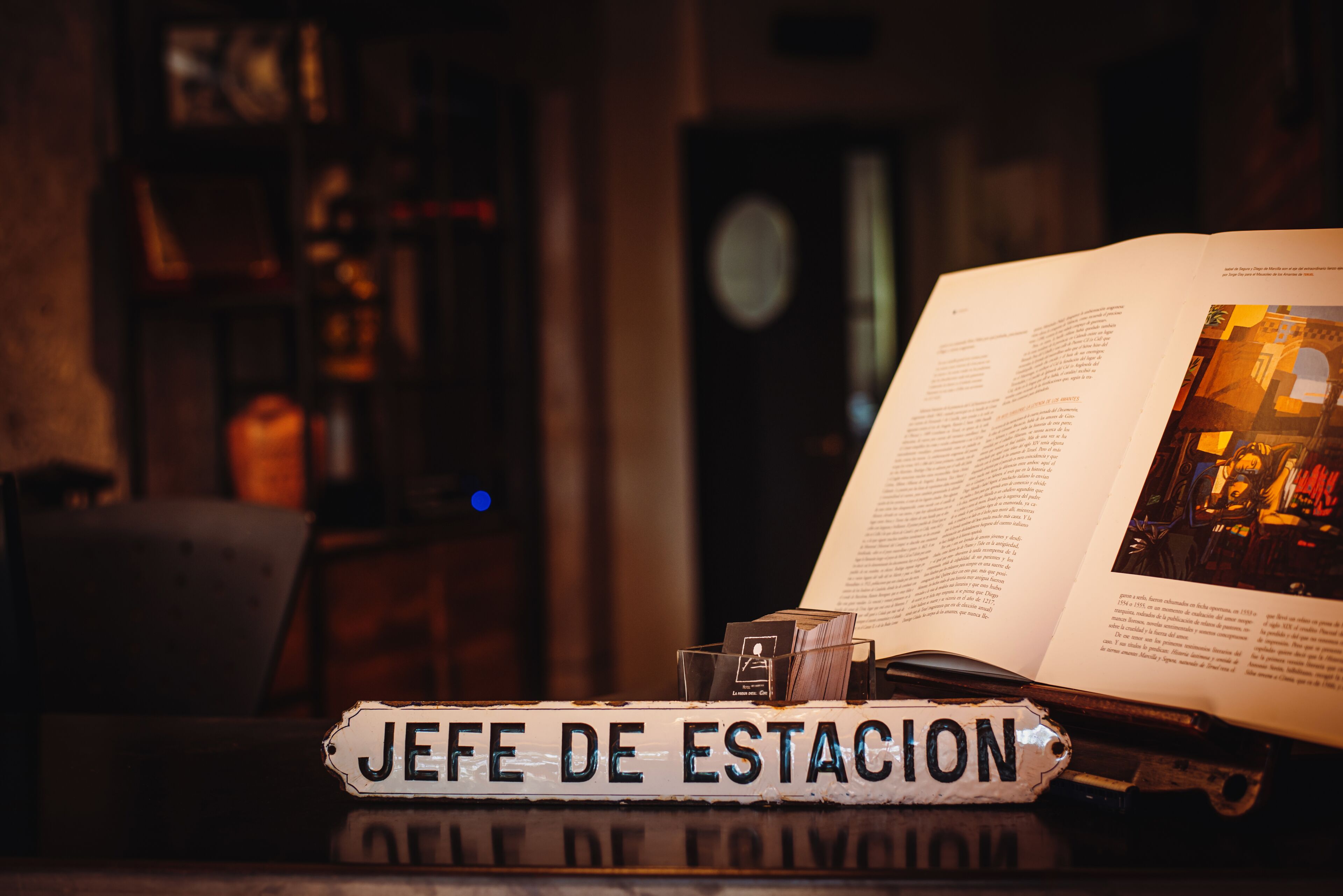 A book titled "JEFE DE ESTACION" on a table with an open book beside it.
