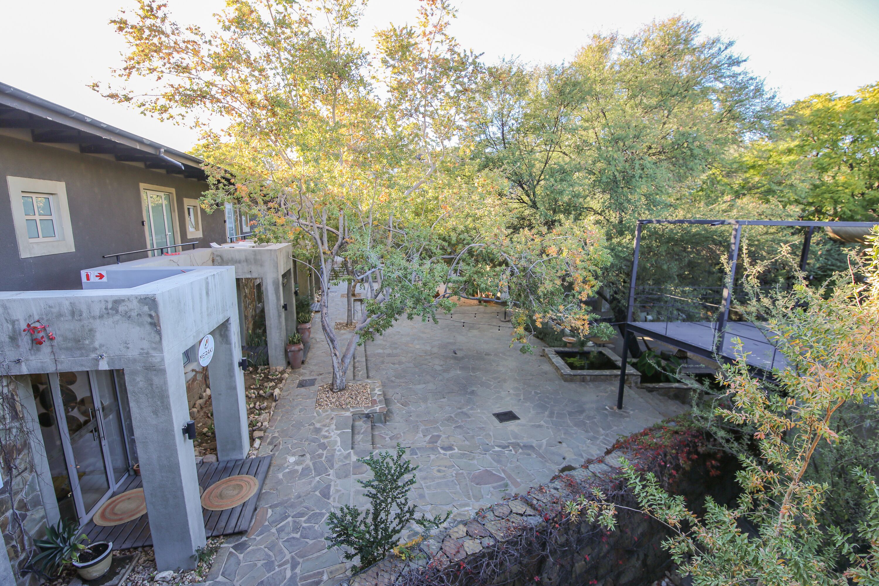 A courtyard with stone flooring, a pergola, and a small seating area.