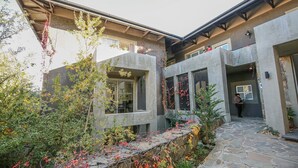 A modern building with a stone pathway leading to a door, surrounded by greenery and plants. - Suite 9 The Village (Windhoek)