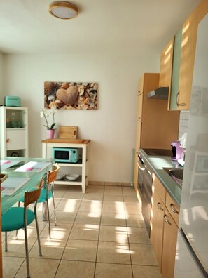 A kitchen with a dining table, chairs, cabinets, and a microwave.