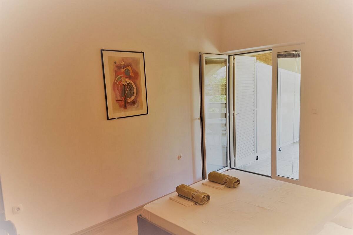 A bedroom with a bed, a window, and a door.