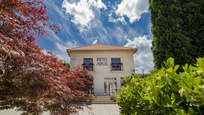 A hotel named "HOTEL ARCE" with a tiled roof, a front entrance, and a visible balcony with flowers.