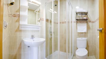 Un baño con ducha acristalada, lavamanos e inodoro.