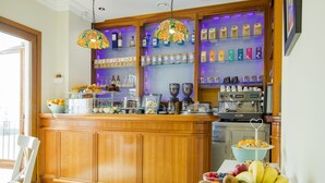 A bar area with a wooden counter, glass shelves with bottles and jars, and a coffee machine.