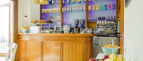 Una zona de bar con mostrador de madera, estantes de vidrio con botellas y frascos, y una máquina de café.